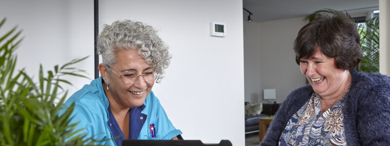 Thuiszorg laptop lach met client